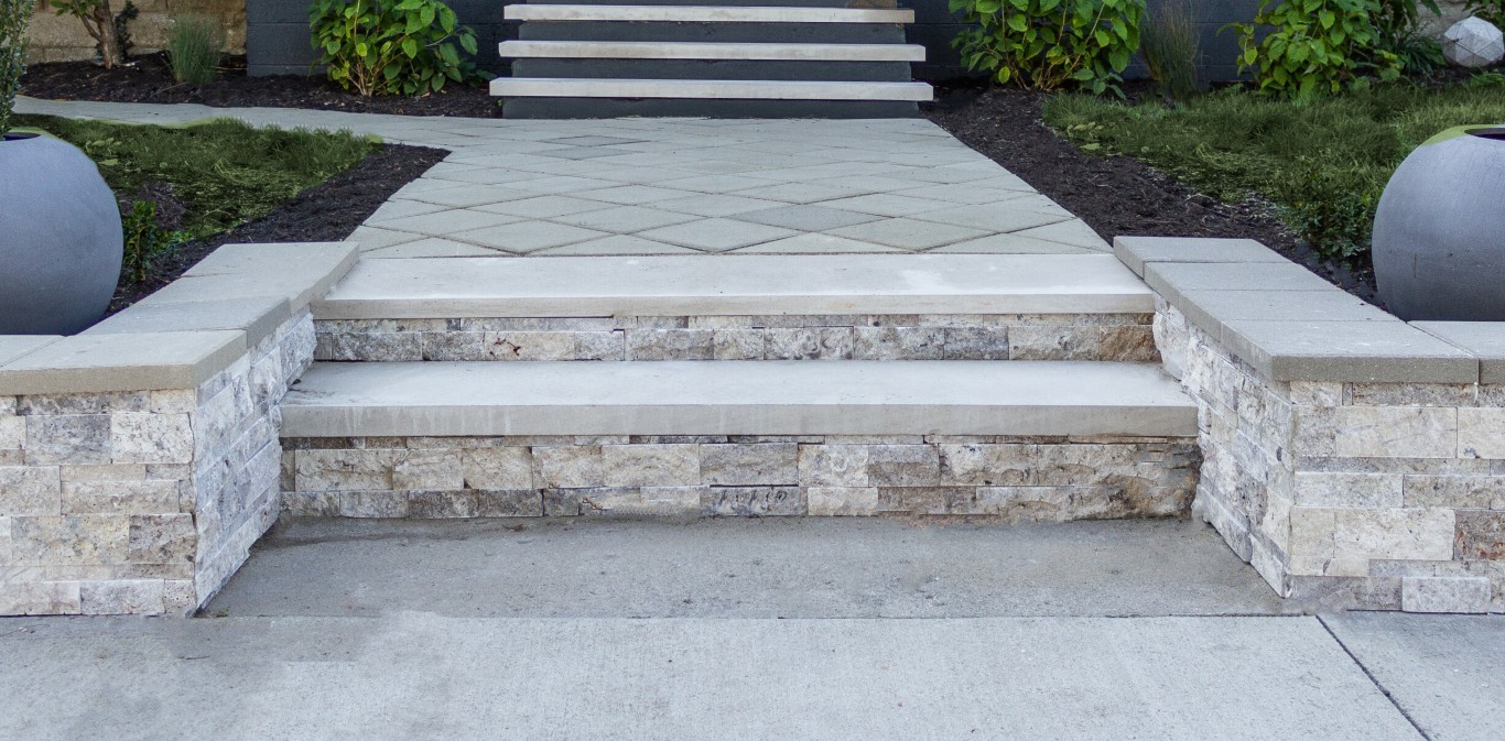 Elegant concrete and stone veneer entry steps with decorative diamond-pattern walkway at residential property