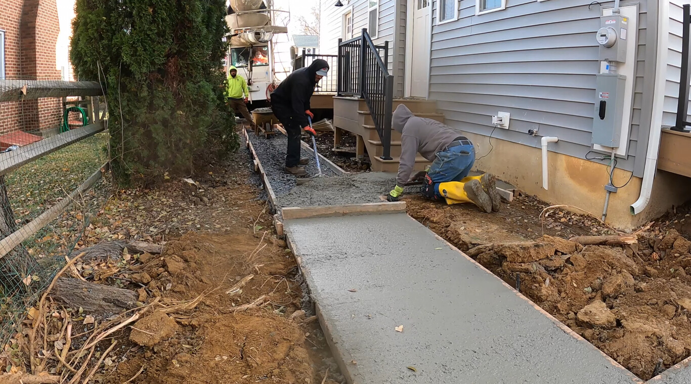 Residential concrete sidewalk and walkway being poured and finished by professional crew