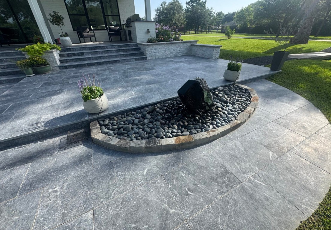 Custom decorative concrete patio with stone water feature and landscape design in residential backyard